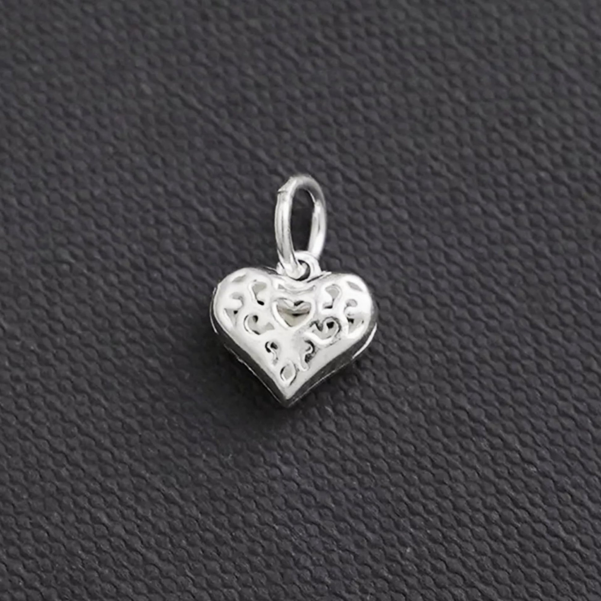 Hollow filigree heart charm pendant in silver tone, side view