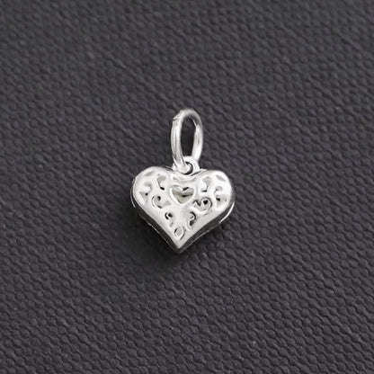 Hollow filigree heart charm pendant in silver tone, side view