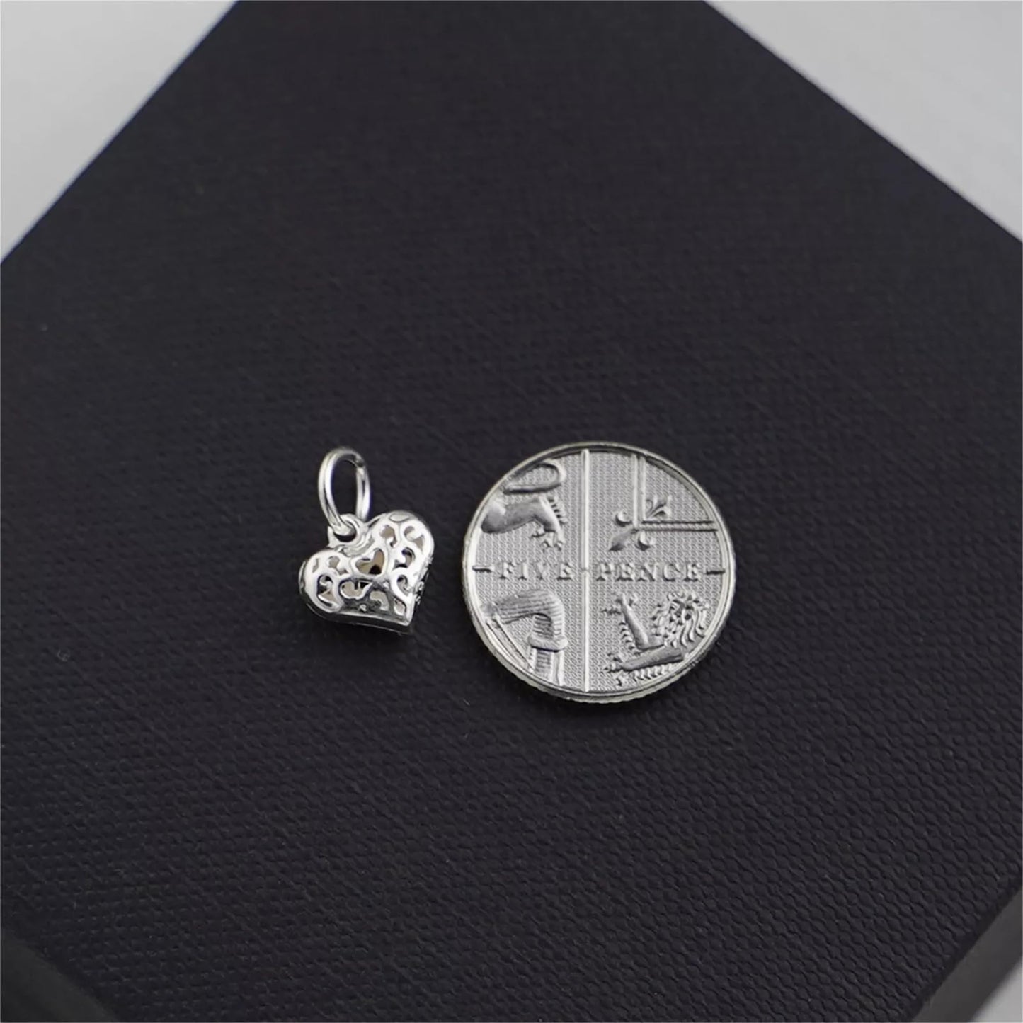 Filigree heart pendant charm beside coin for size reference