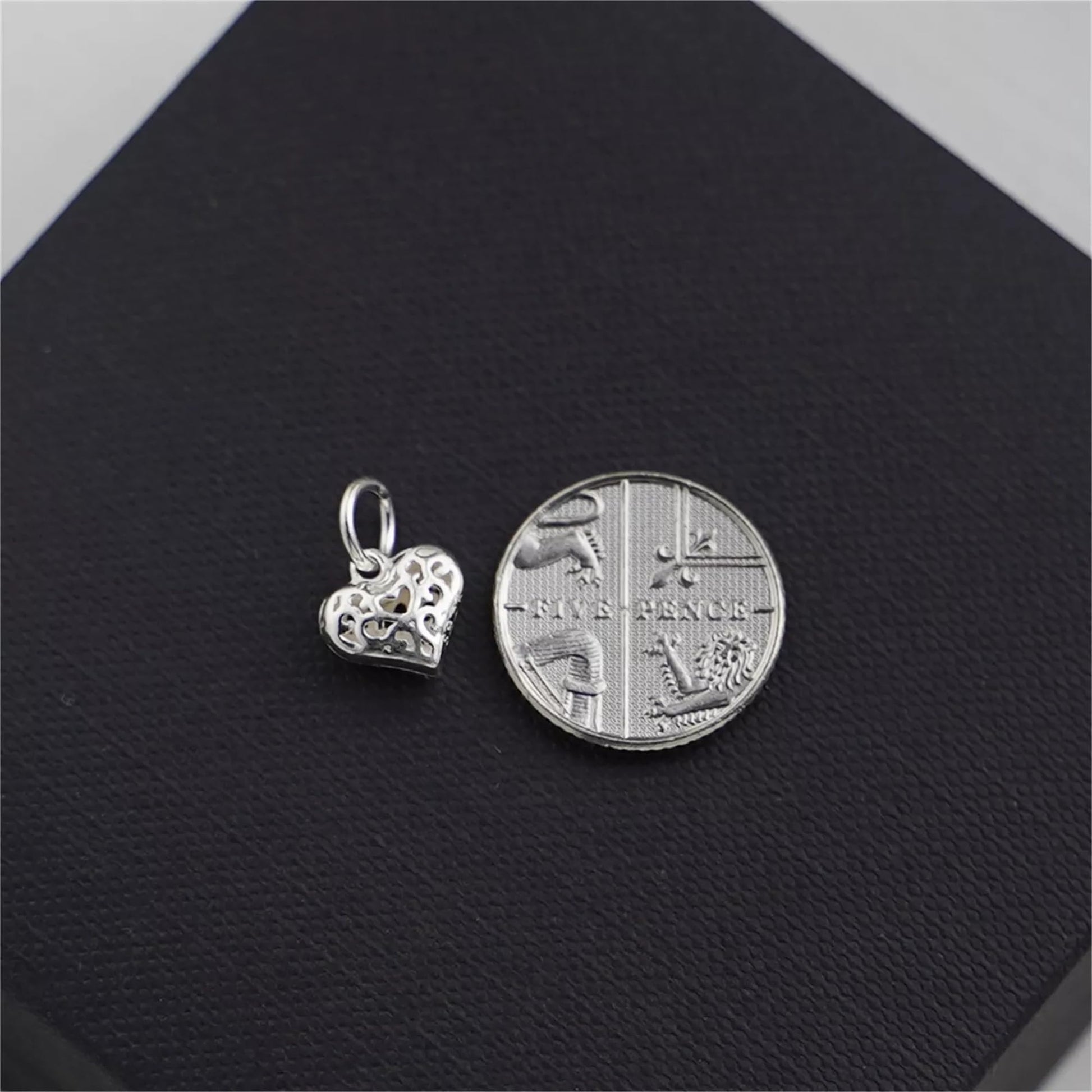 Filigree heart pendant charm beside coin for size reference