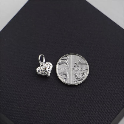 Filigree heart pendant charm beside coin for size reference