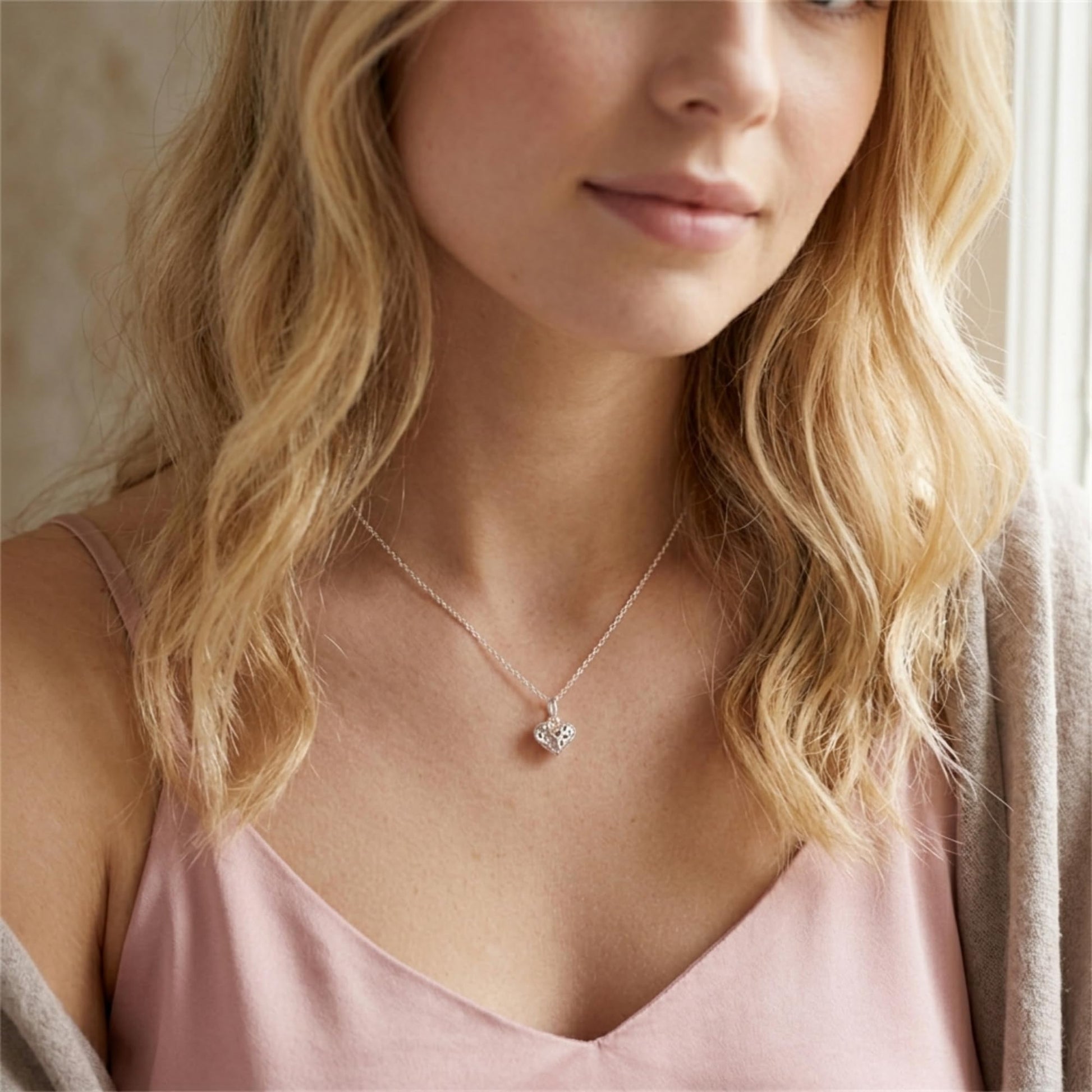 Silver heart pendant necklace with filigree heart charm on collarbone
