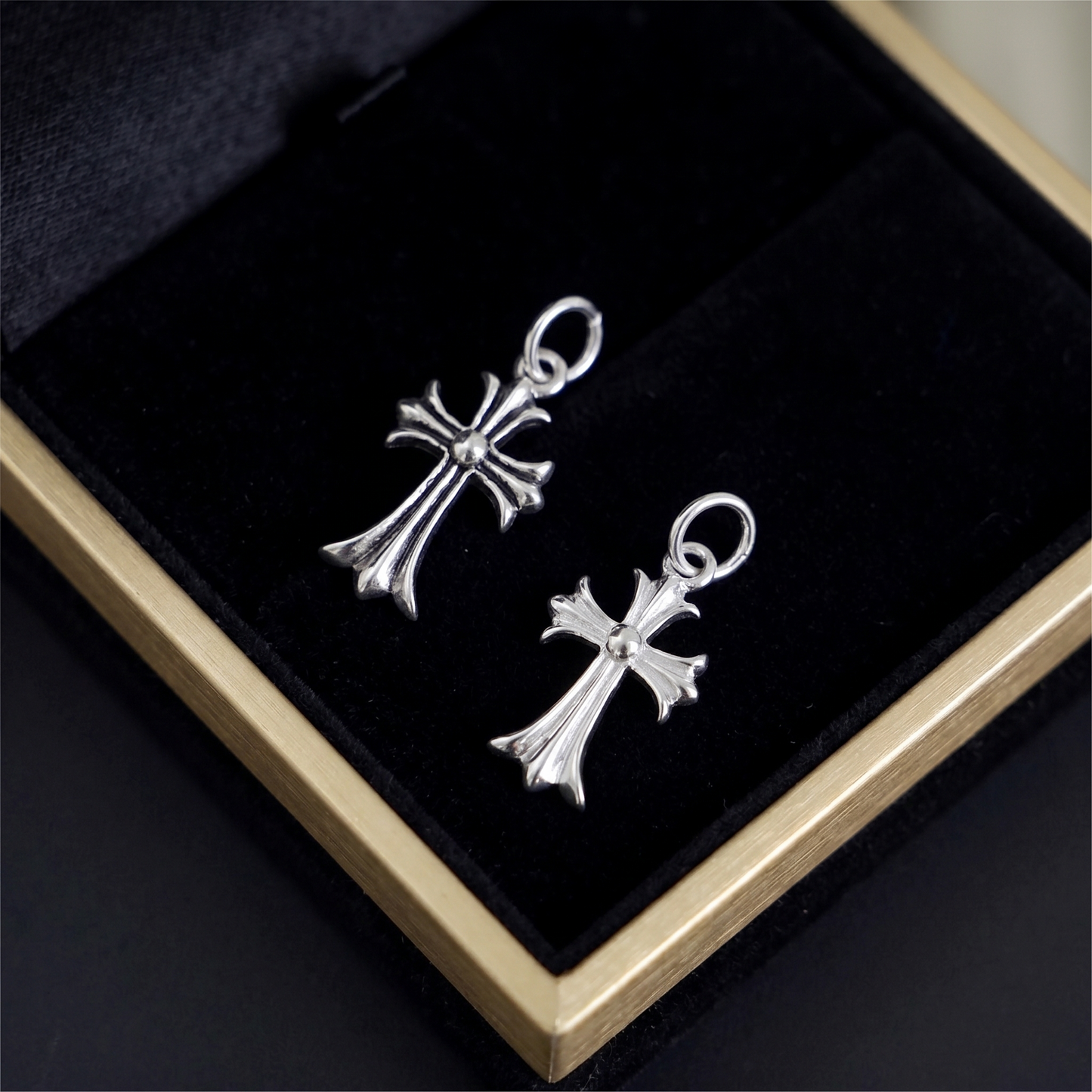 Two-tone fleur-de-lis cross charm hook earrings, silver cross design close-up