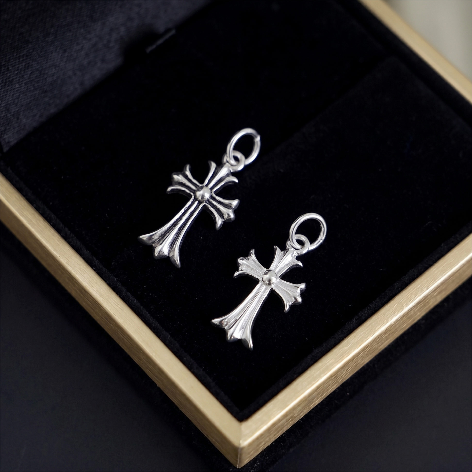 Two-tone fleur-de-lis cross charm hook earrings, silver cross design close-up