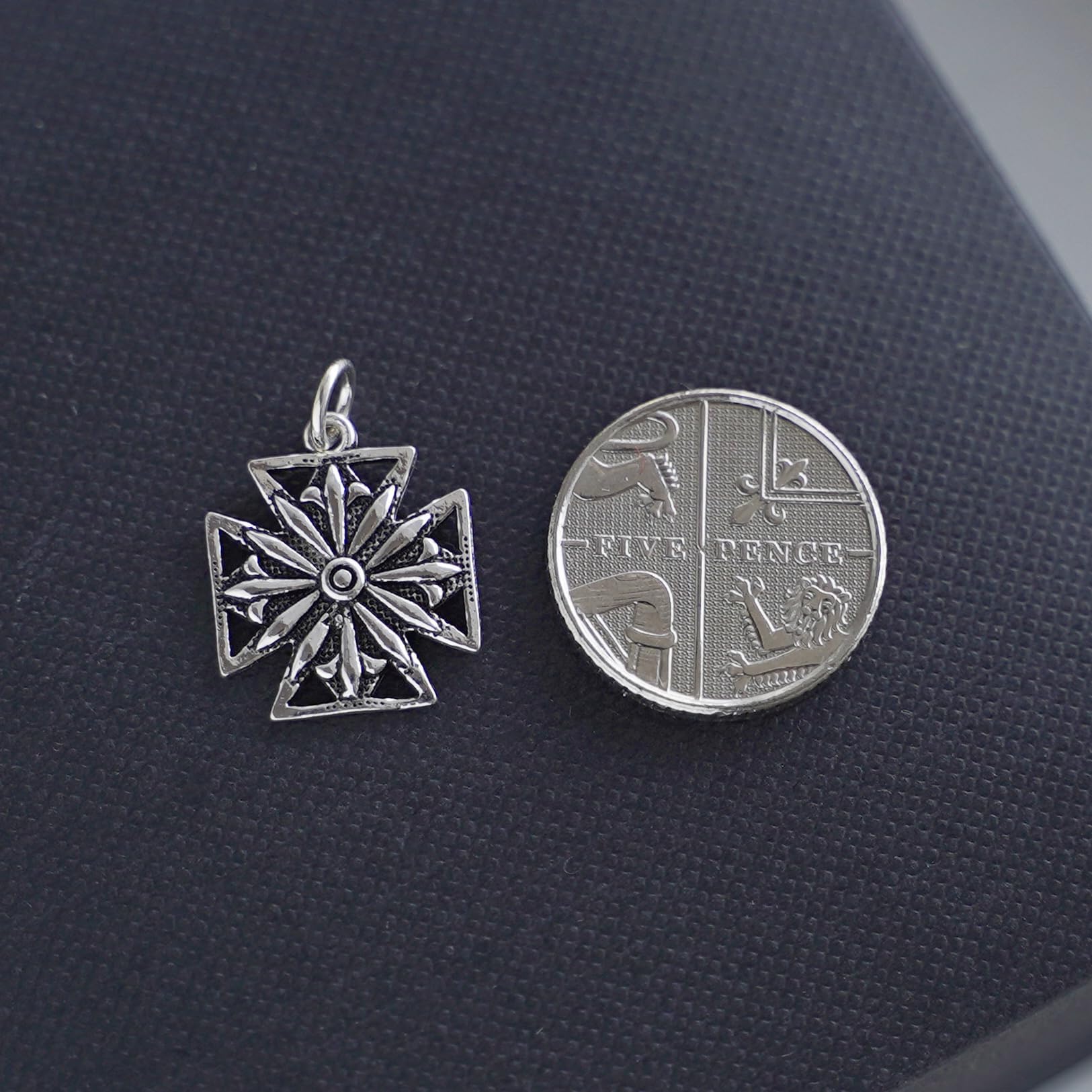 Oxidised Maltese star pendant beside coin-style reverse charm, silver tone