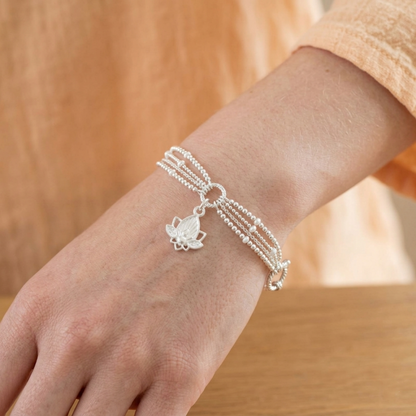Lotus flower charm bracelet with silver chain and small lotus pendant on wrist