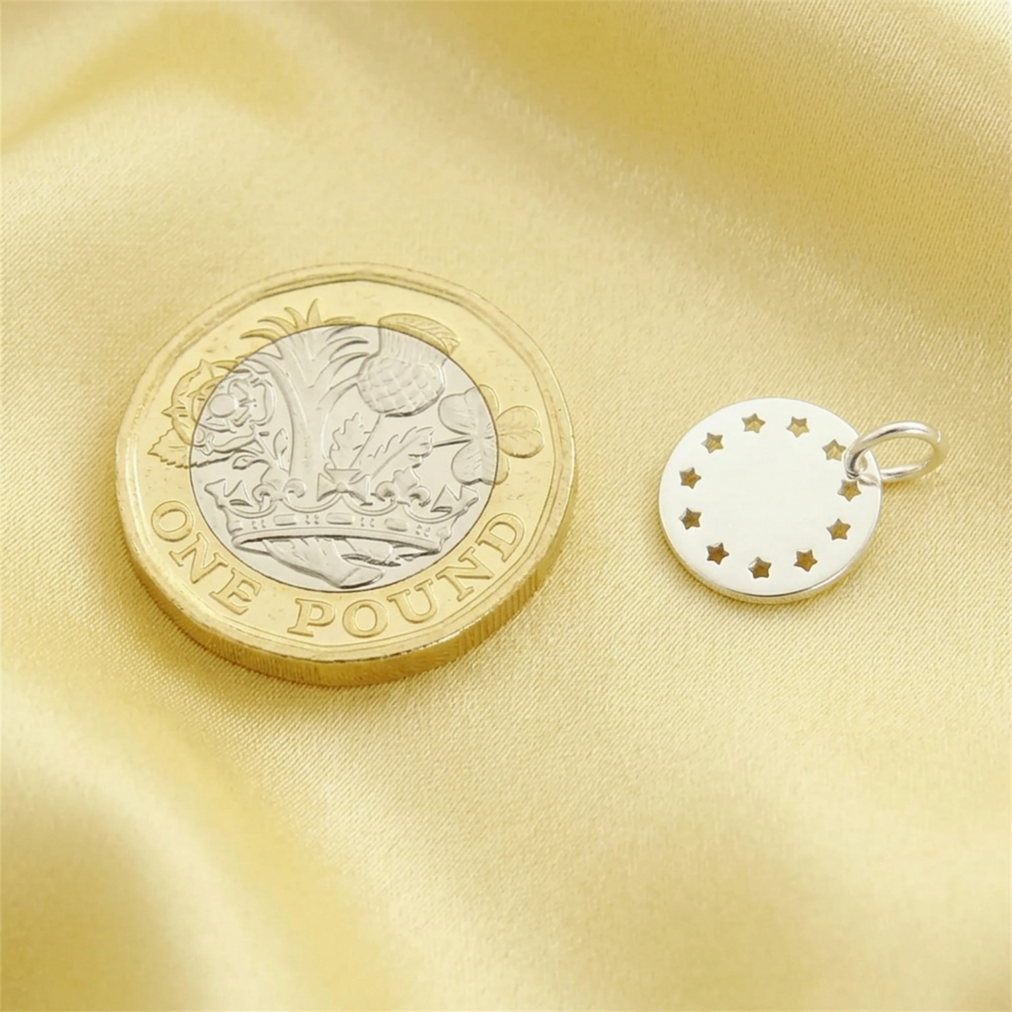 Small silver round charm disc with star cutouts and an attached metal loop