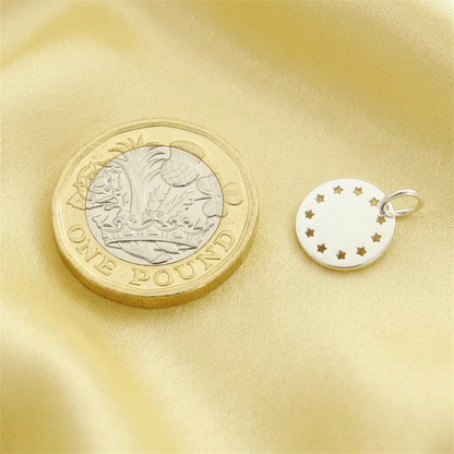 Small silver round charm disc with star cutouts and an attached metal loop