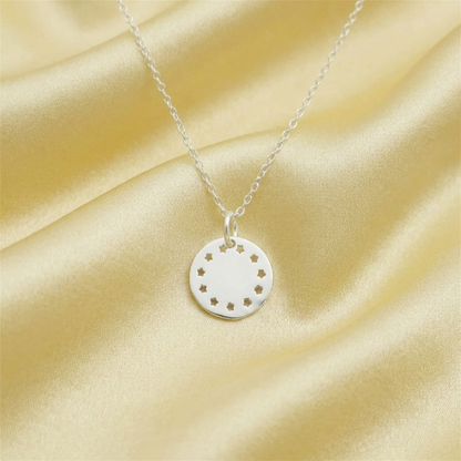 Silver necklace with a round pendant charm disc featuring small star cutouts