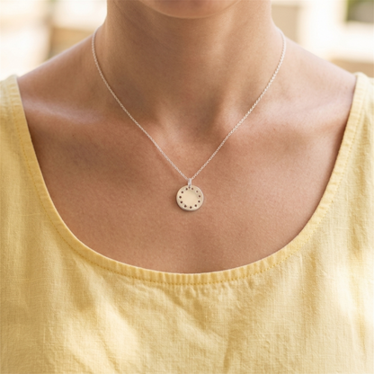 Silver pendant necklace with a round disc charm featuring a dotted design