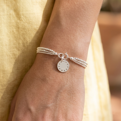 Silver charm bracelet with a round disc pendant and small star cutouts