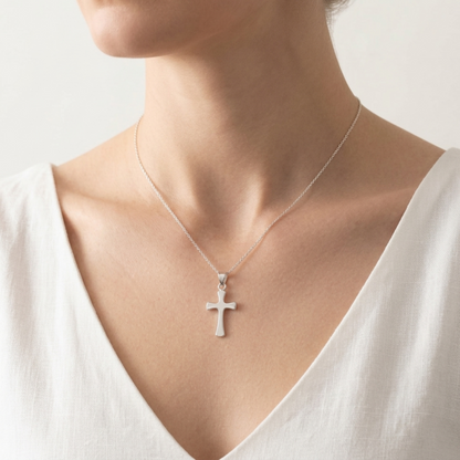 Cross pendant on a fine chain, worn on the neck over a light V-neck top