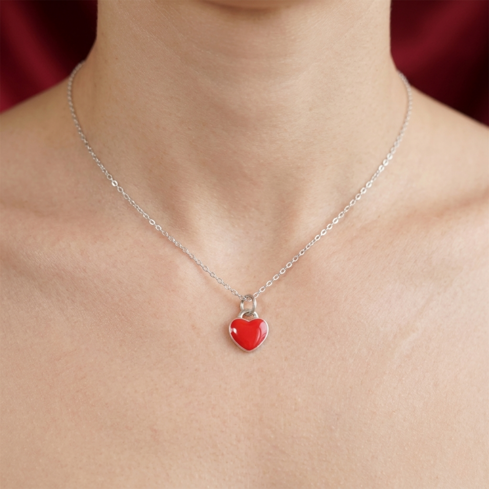 Silver chain necklace with red heart charm pendant on neckline