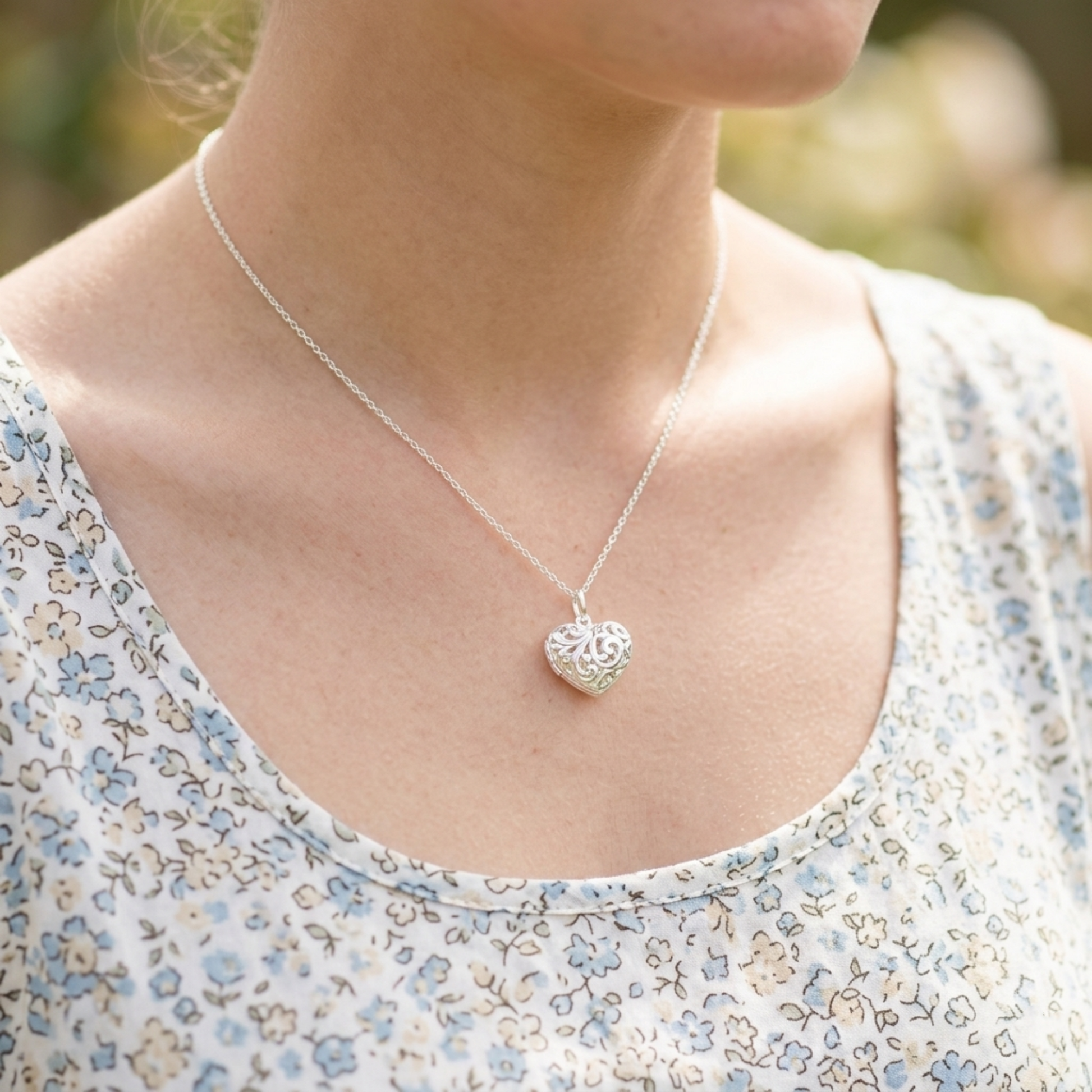 Silver heart pendant necklace on a model, featuring filigree heart centerpiece