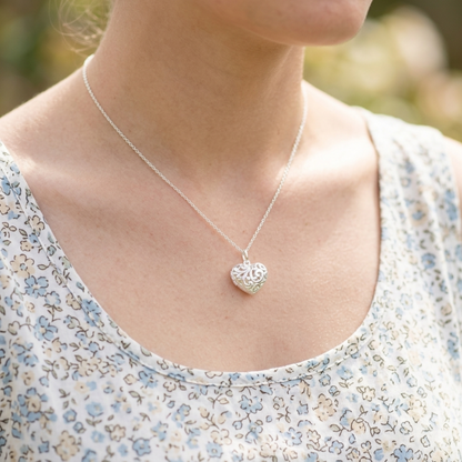 Silver heart pendant necklace on a model, featuring filigree heart centerpiece