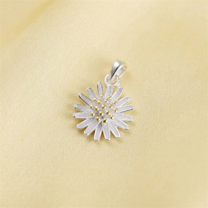 Silver daisy flower pendant on pale fabric, gold center and petal details