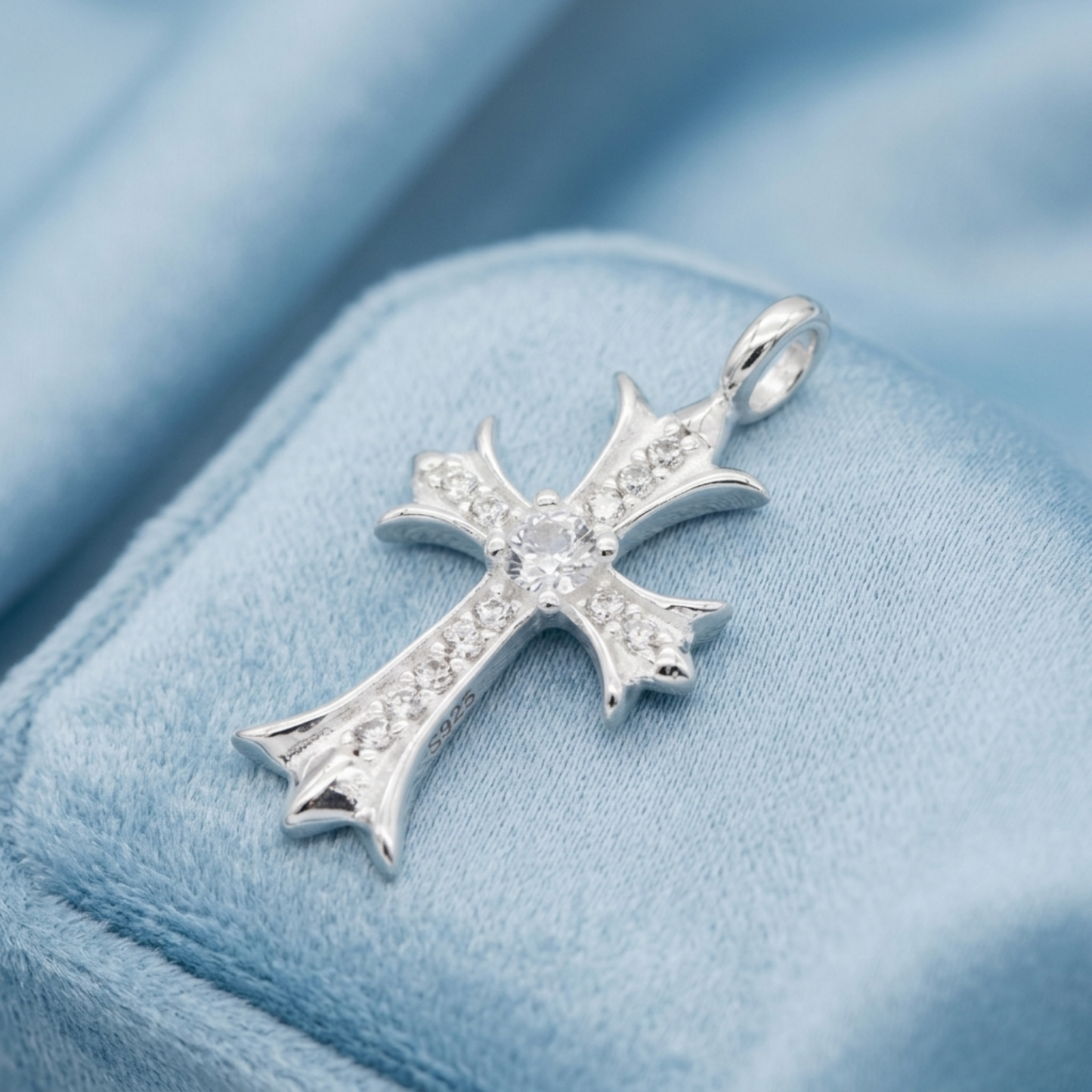 Silver cross pendant with pavé stones and round center, on blue velvet