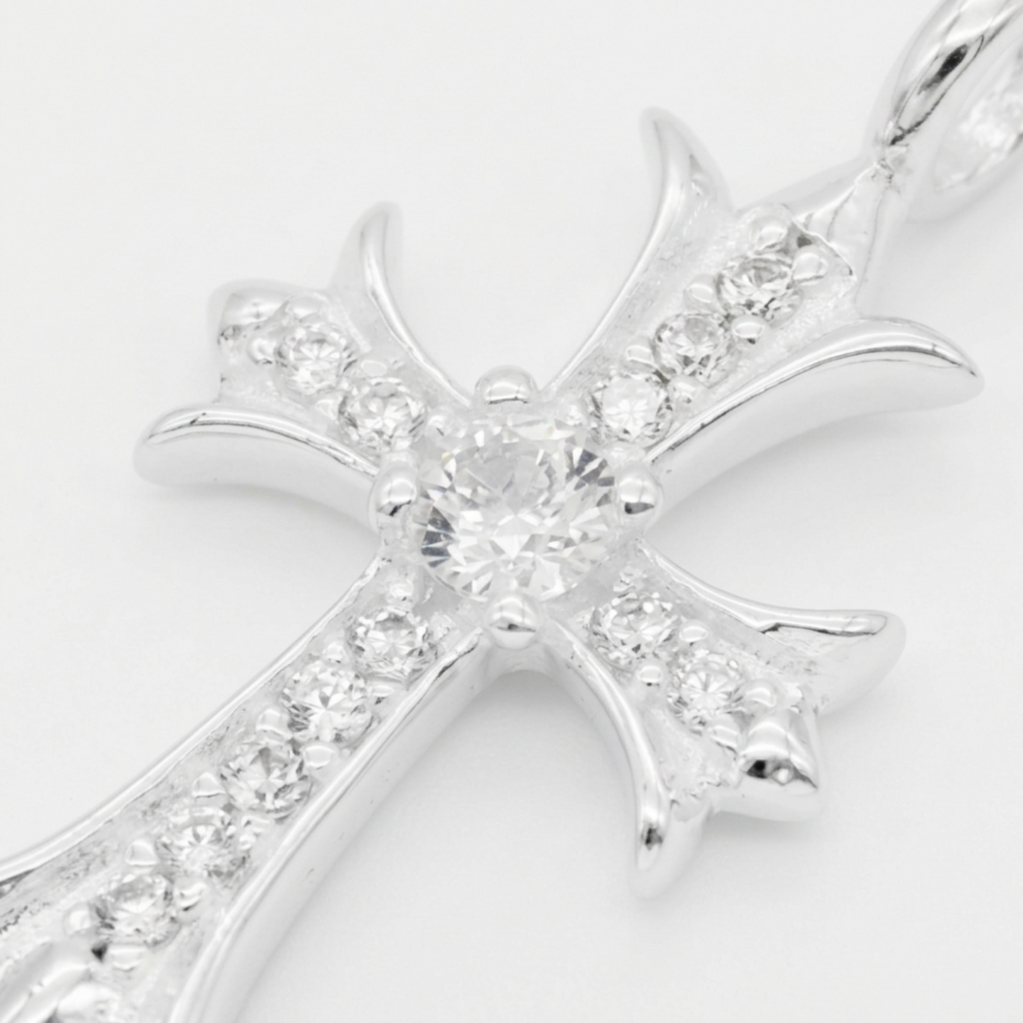 Close-up of silver cross pendant center with round stones and surrounding pavé