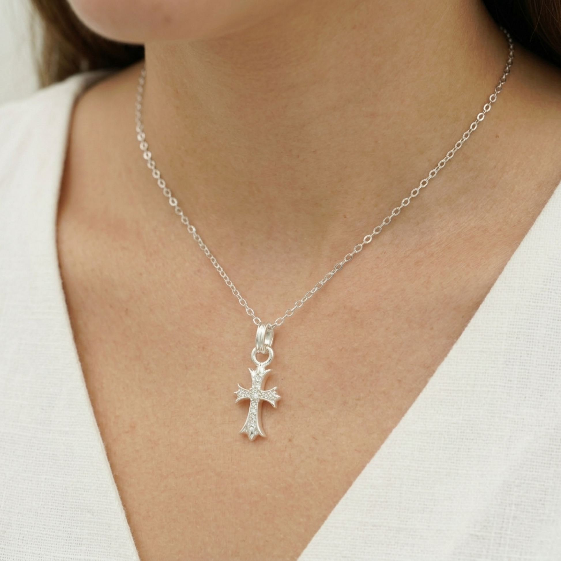 Silver cross pendant on a chain necklace with a round center and small pavé stones