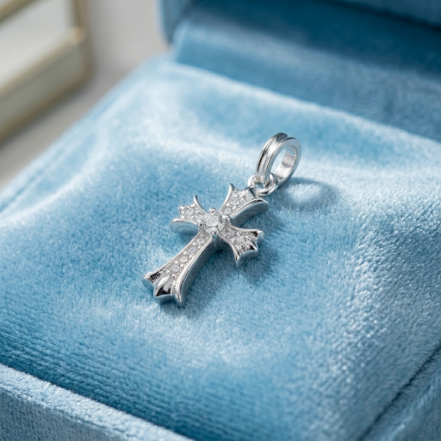 Silver cross pendant with pavé stones and round center, on blue velvet