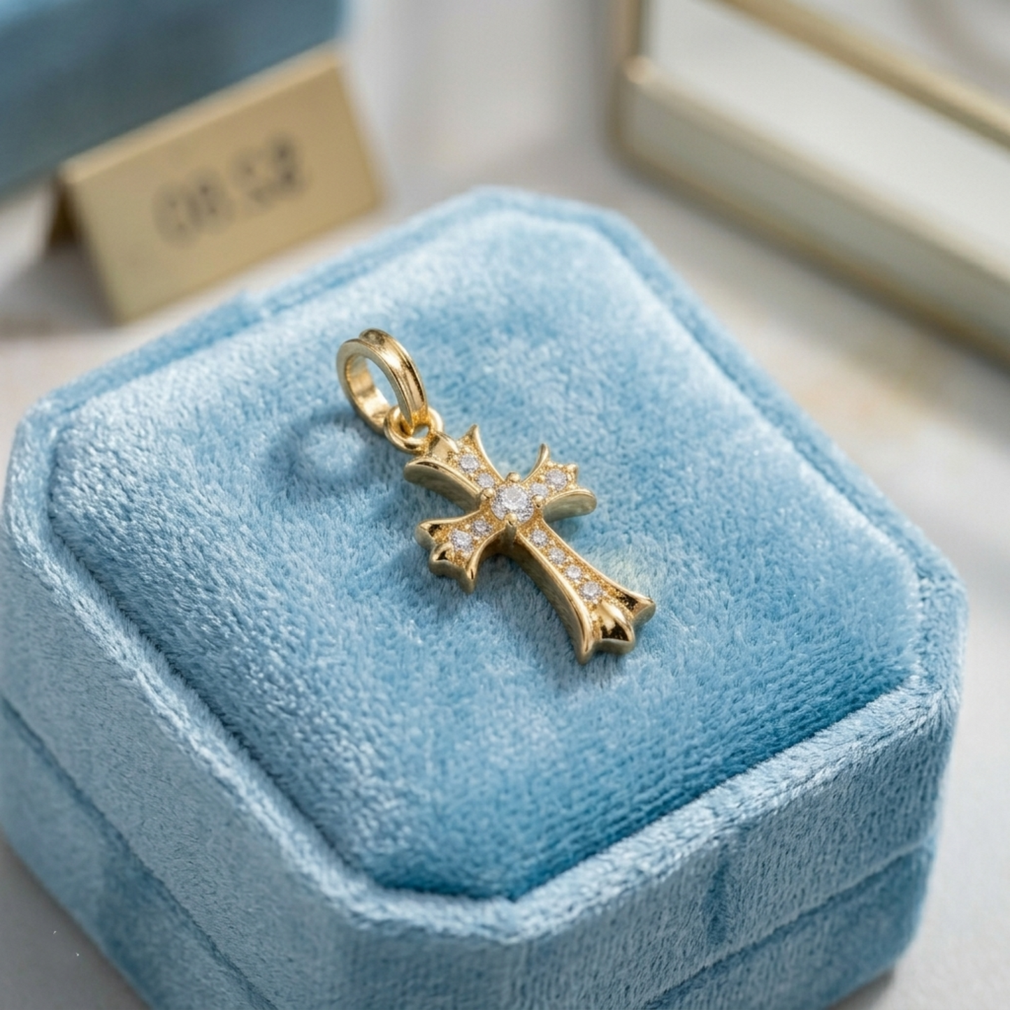 Gold cross pendant with sparkle pavé stones and round center, on blue velvet