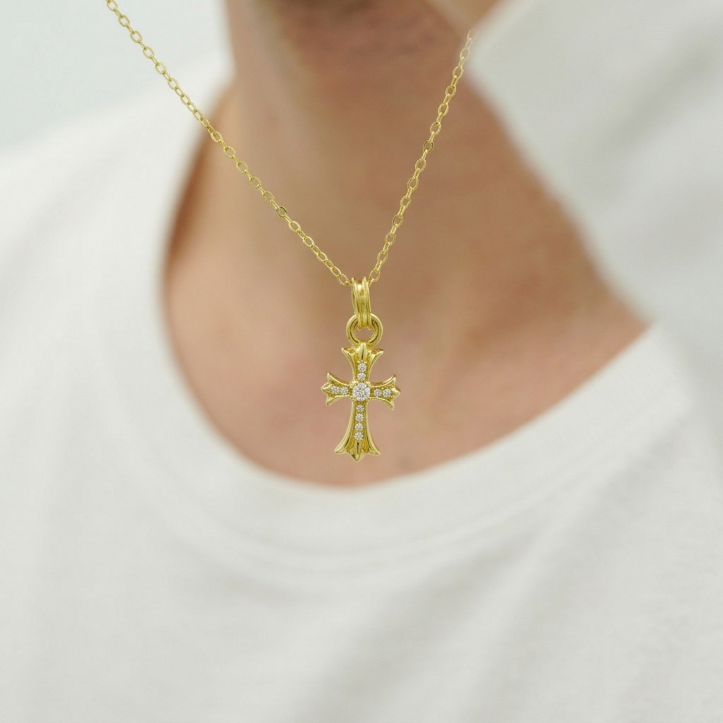 Gold cross pendant on a chain necklace with small pavé stones and round center