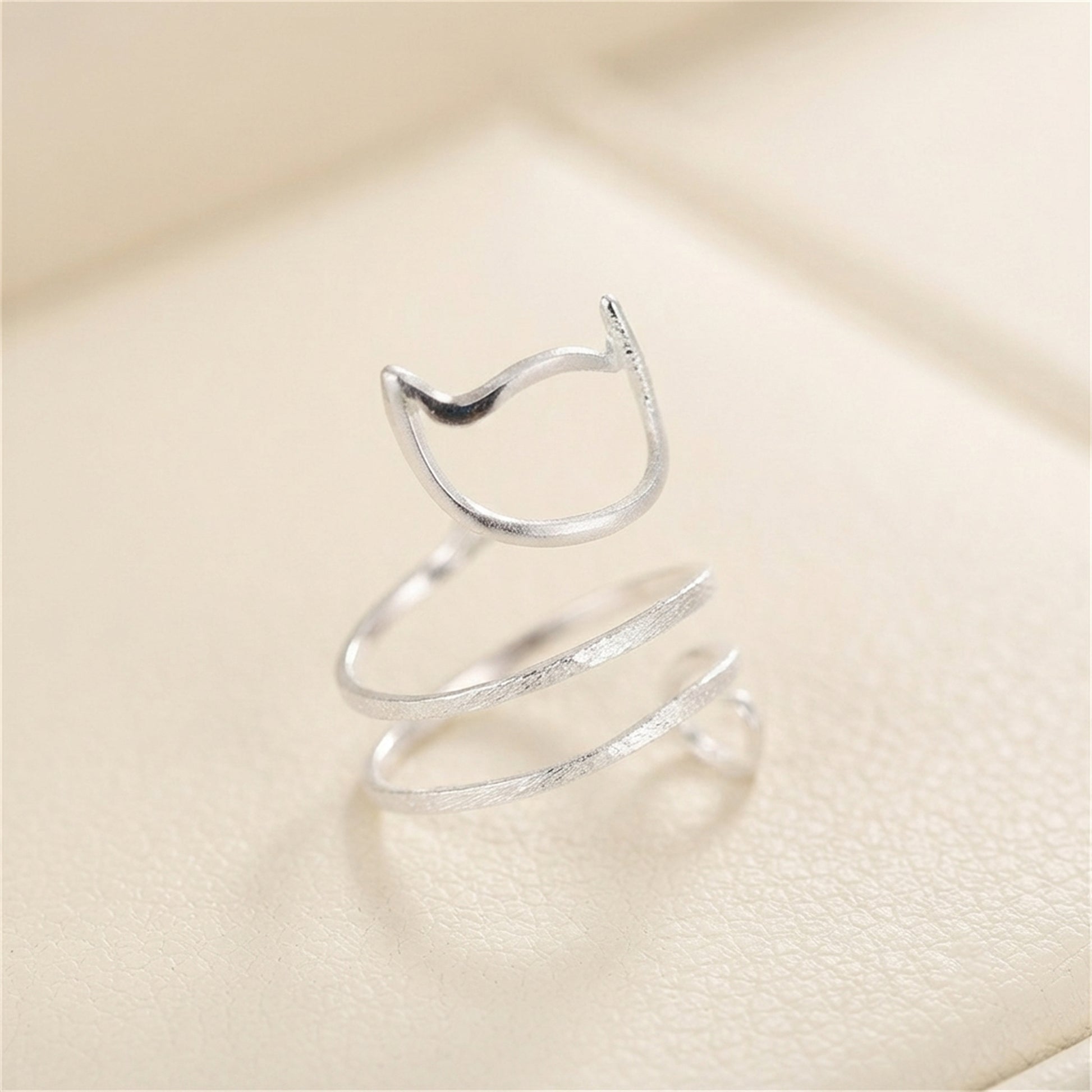 Silver-tone kitten wraparound ring viewed from above, cat-face and spiral tail.
