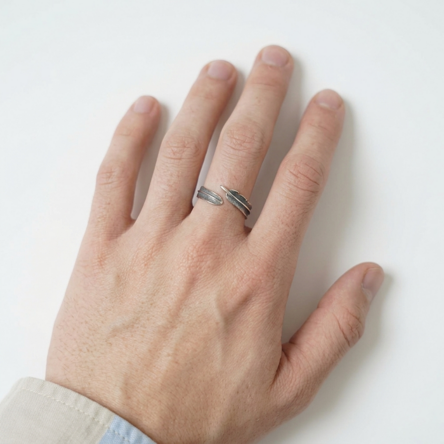 Silver feather wrap ring on hand, two narrow stacked bands with leaf-feather detail