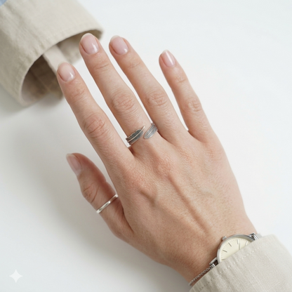 Silver feather wrap rings on hand with smartwatch band partially visible