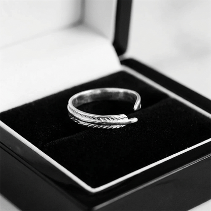 Silver feather wing open ring displayed on a black jewelry tray