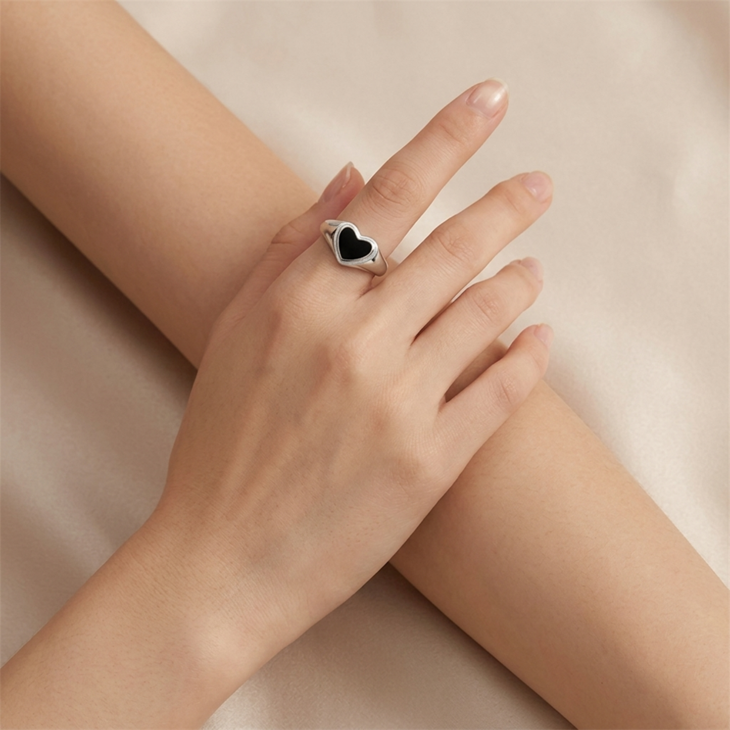 Silver heart ring with black heart inset on open hand