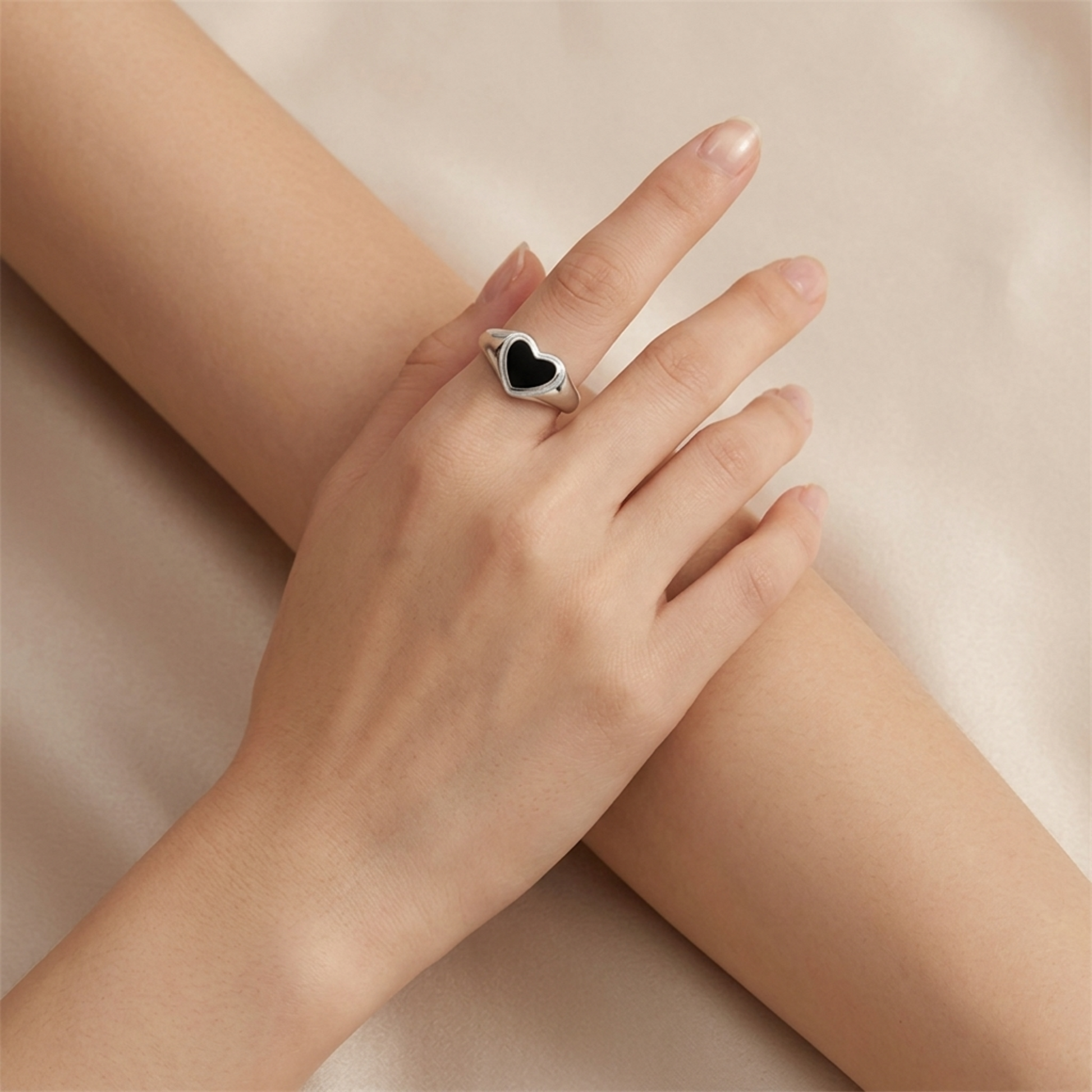 Silver heart ring with black heart inset on open hand