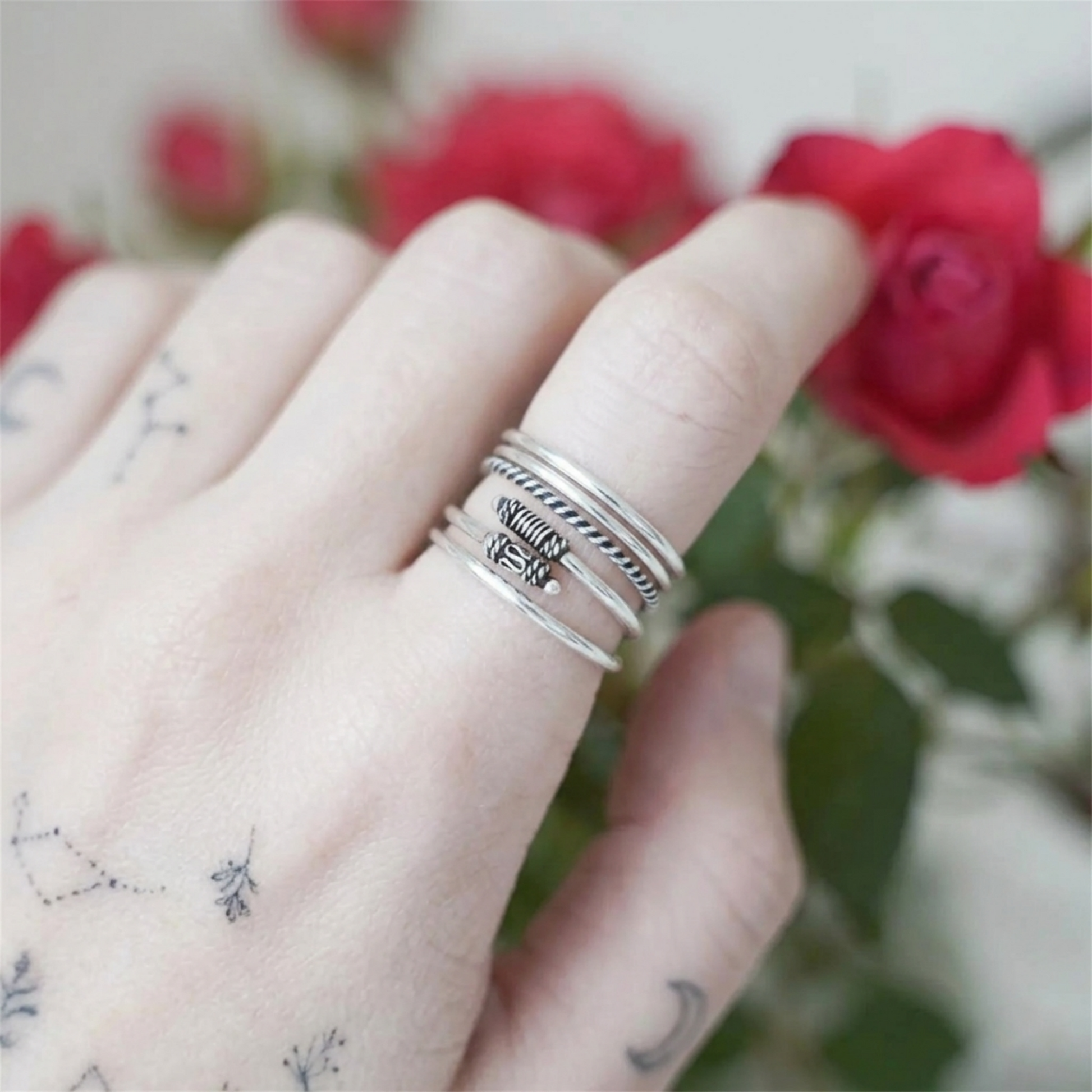 Oxidized silver totem knot ring stacked on finger with ridged texture and knot