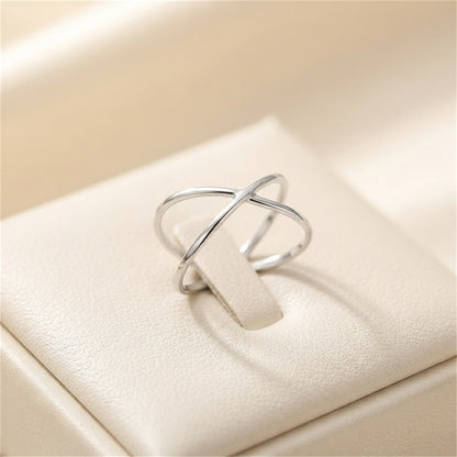 Silver criss-cross love knot ring with crossed bands, angled view.