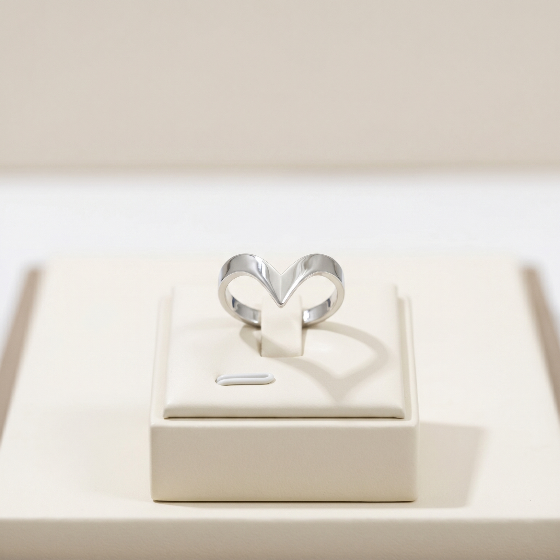 Silver wishbone V ring on a white jewelry box, open V shape with smooth edges.