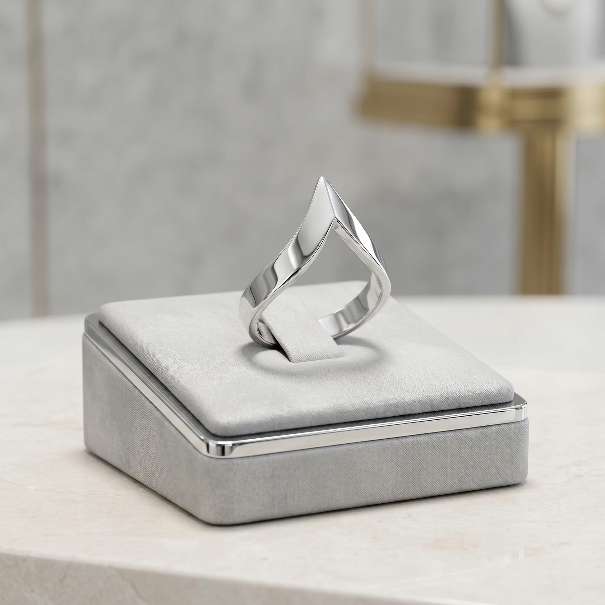 Silver wishbone V ring resting on a gray jewelry box cushion, polished finish.