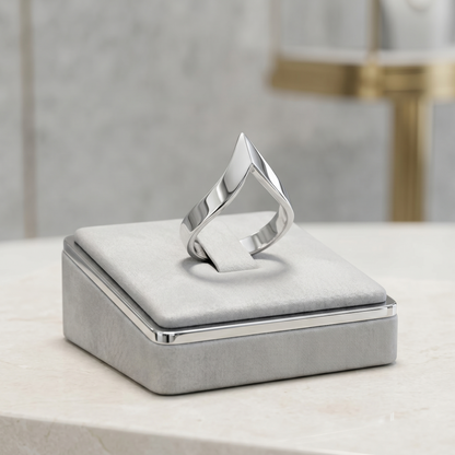 Silver wishbone V ring resting on a gray jewelry box cushion, polished finish.