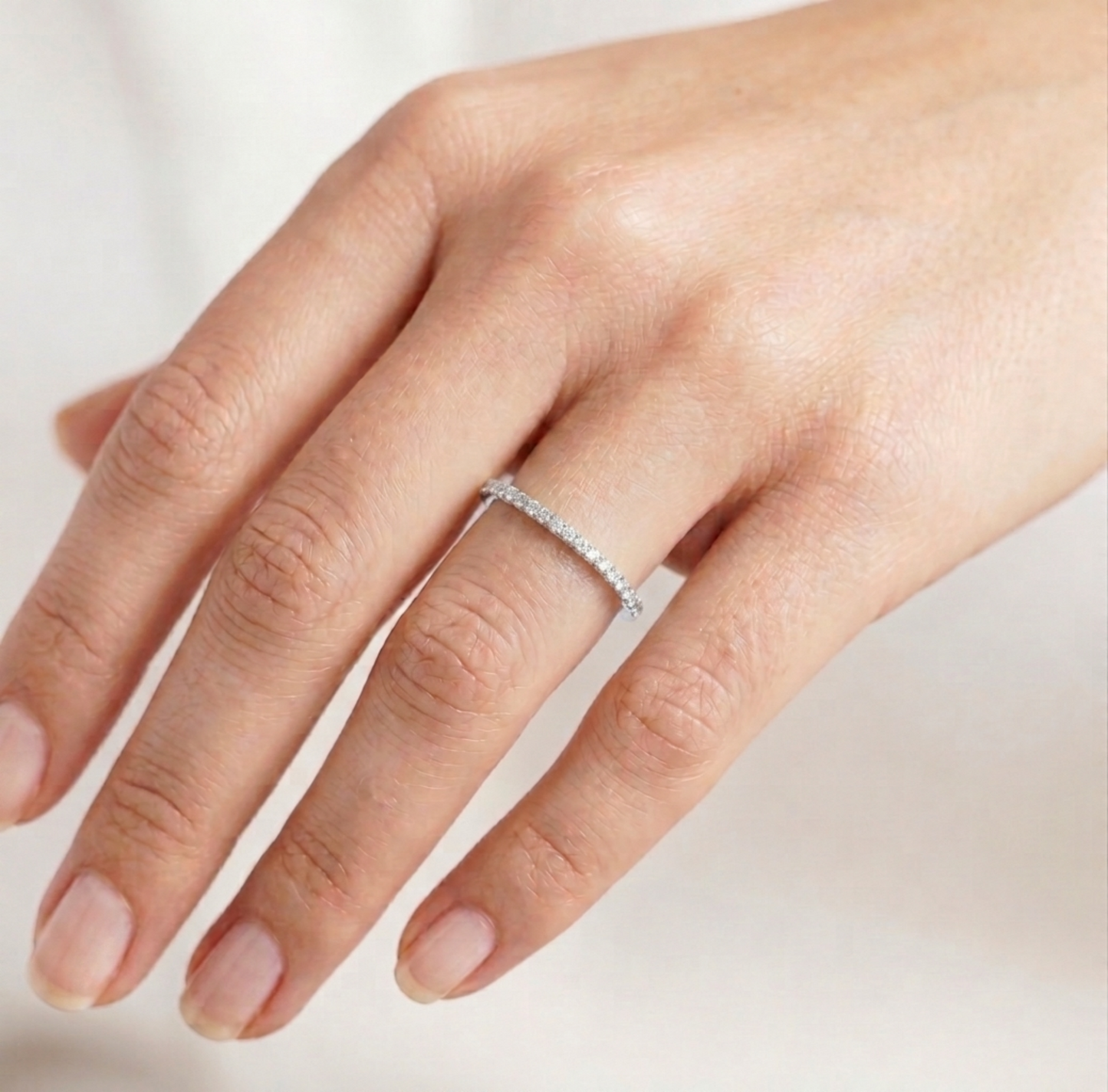 Rhodium pavé stack ring on finger, slim polished band with pavé stones.