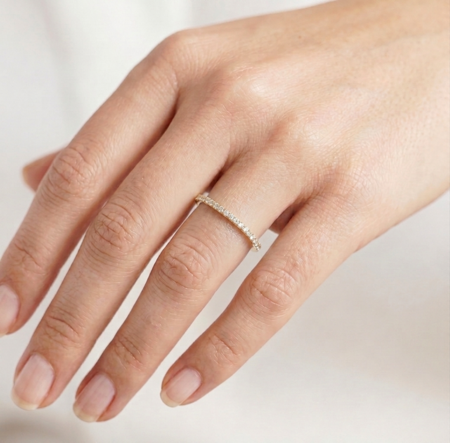 Rose gold pavé stack ring on finger, thin hoop with sparkling stone pavé.