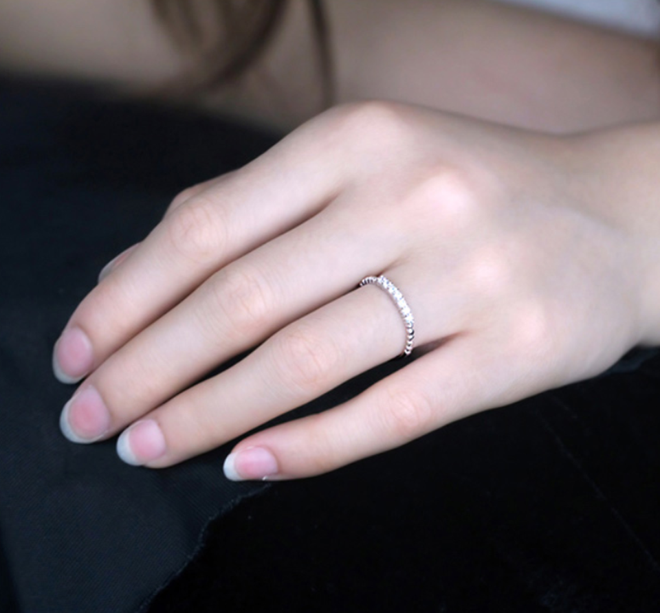 Silver half-eternity beaded ring with clear stones, shown on hand.