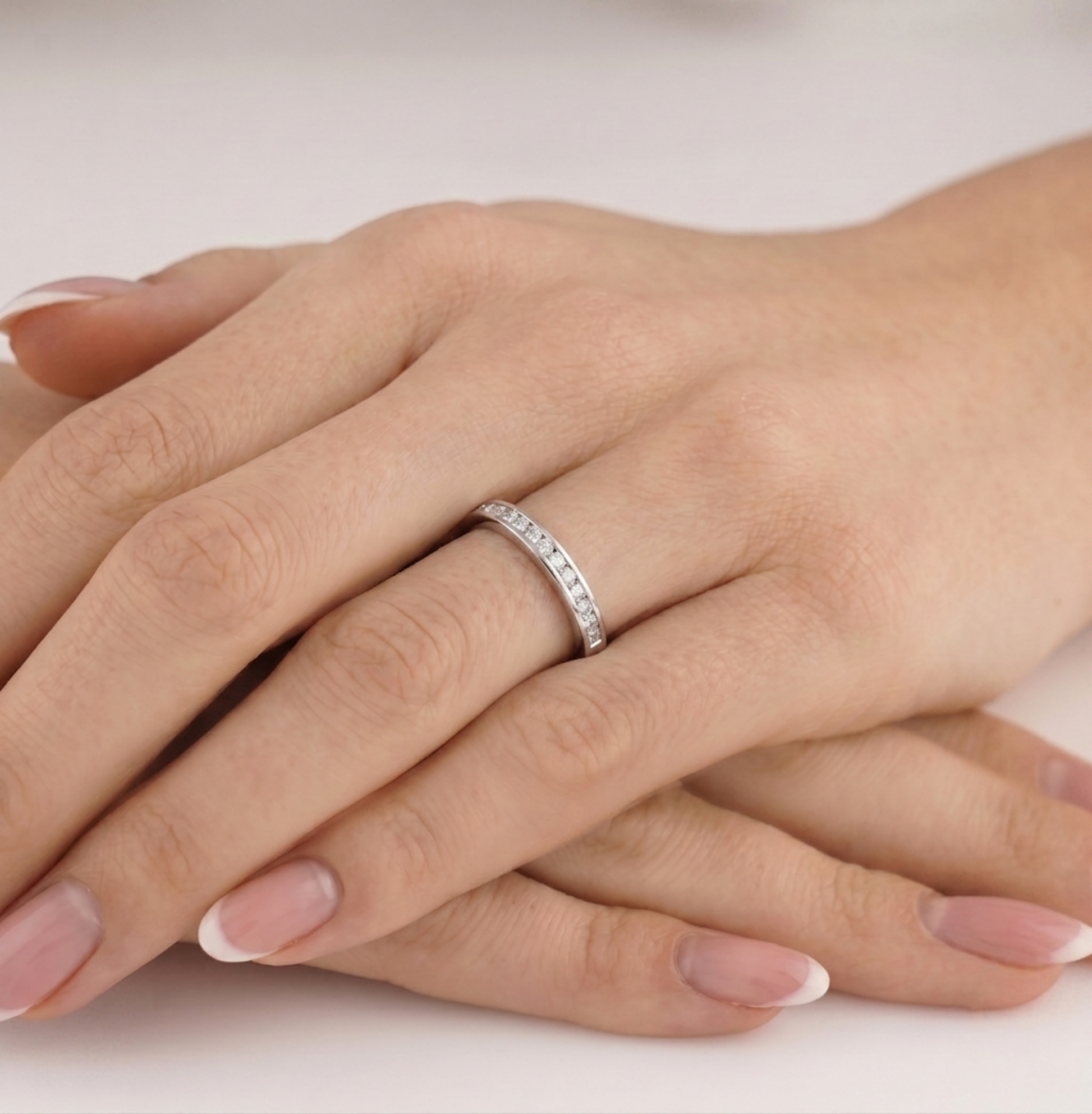 Silver eternity ring with a row of round stones along the band, worn on finger