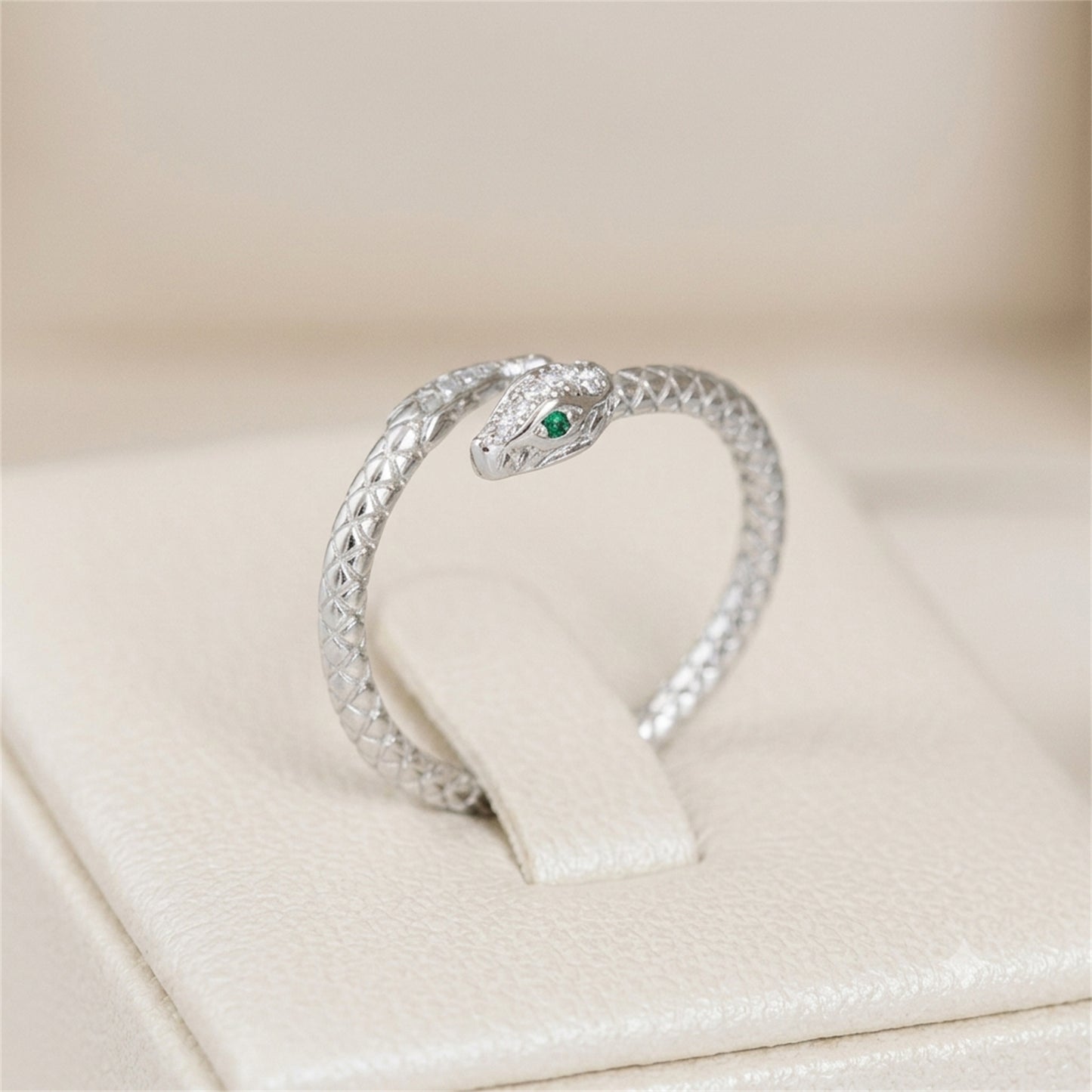 Silver-tone snake wrap ring with green eye and clear stone details