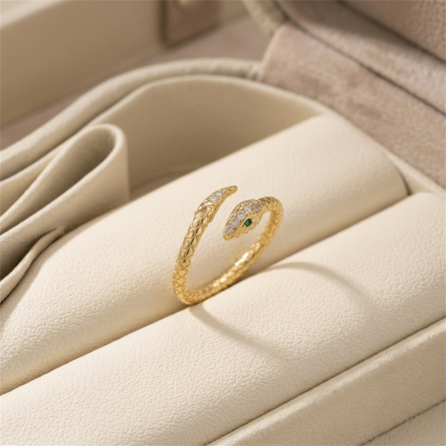 Gold-tone snake wrap ring with green eye and small clear stones