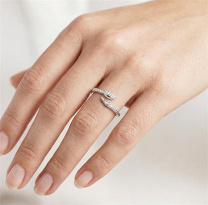 Silver-tone snake wrap ring on hand with green eye and clear stones