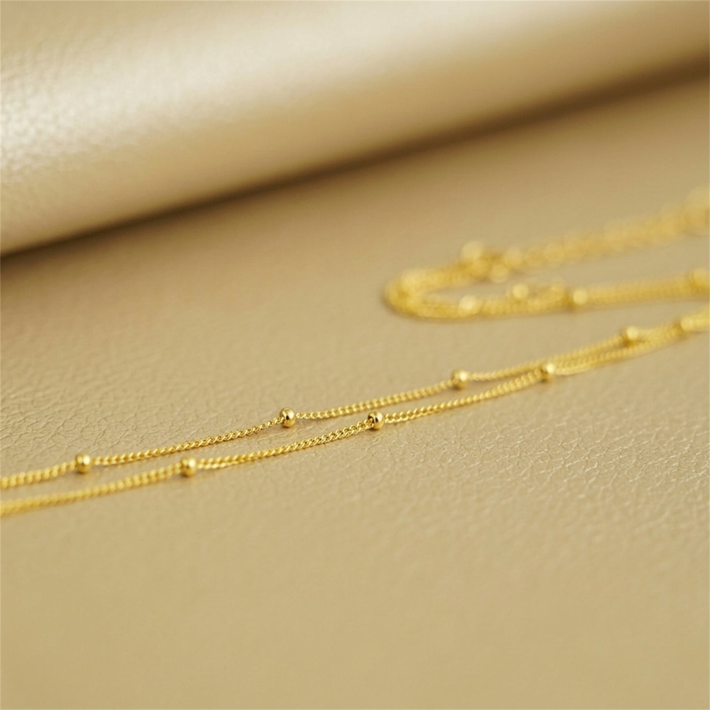 Gold beaded satellite chain necklace, small round bead links in a flat line.