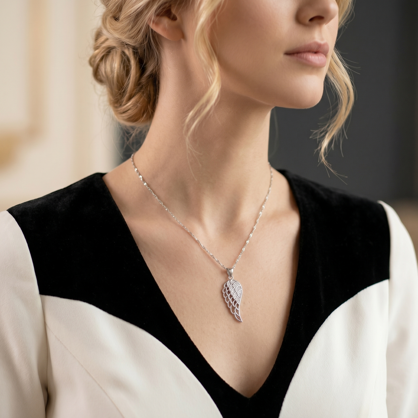 Angel wing pendant worn on a model’s necklace, pavé feather design