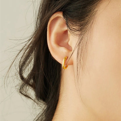 Small gold hoop earrings with latch-back clasp on ear