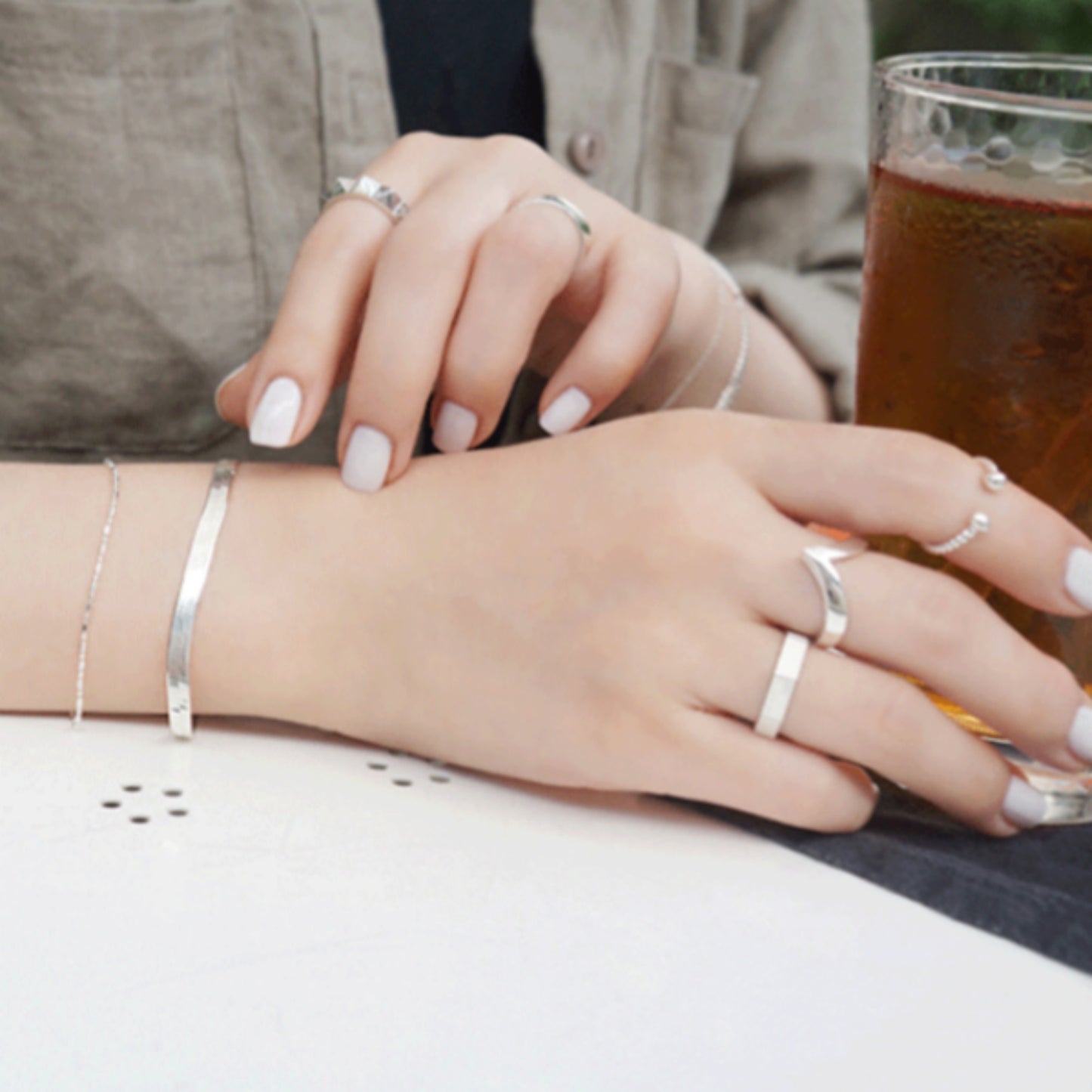 Silver wishbone V ring on fingers with white nails, open V shape on top.