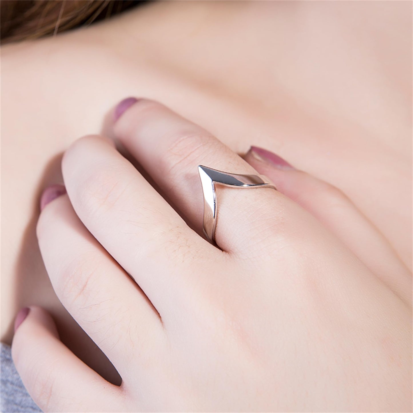 Silver wishbone V ring on a hand, open V tip shape at the finger.