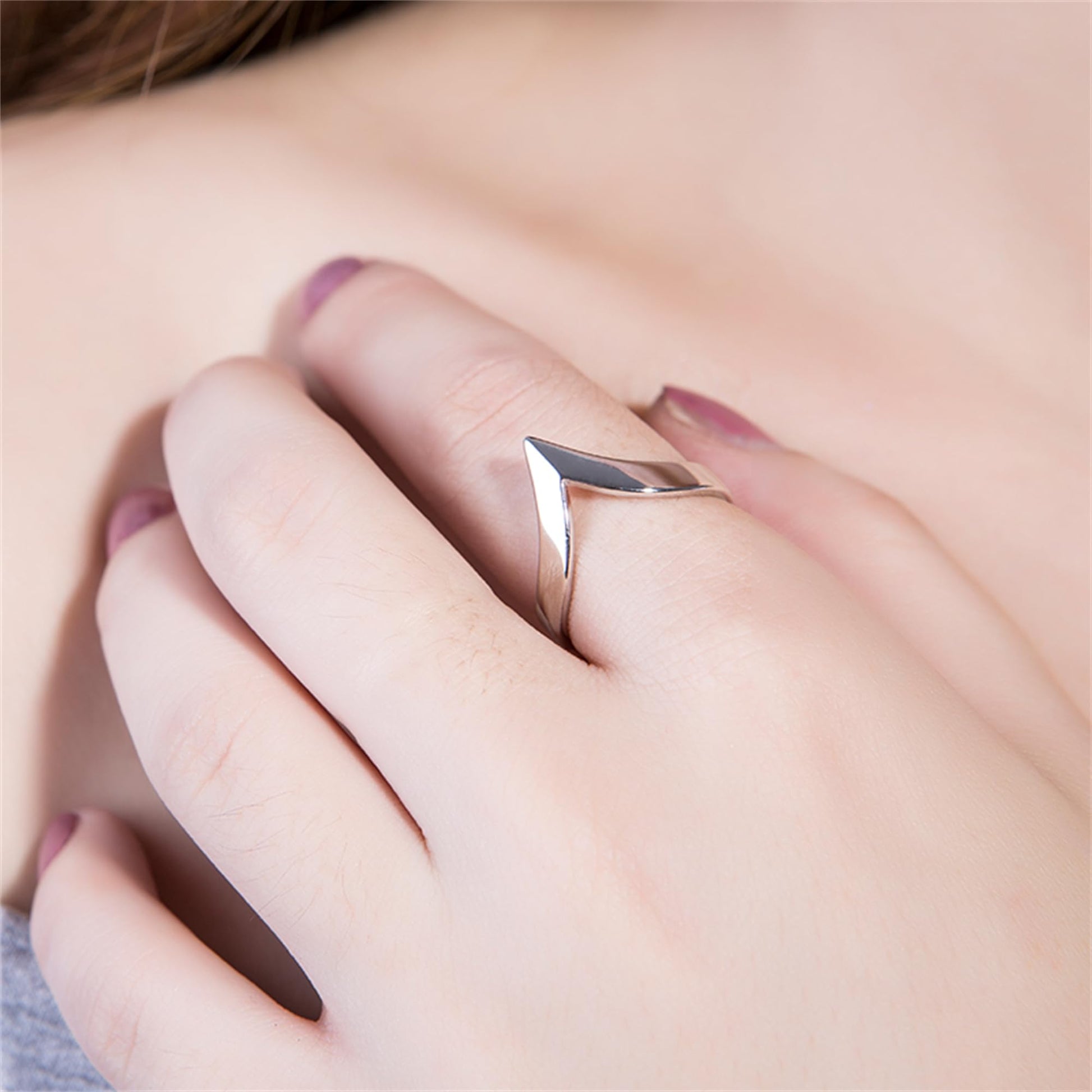 Silver wishbone V ring on a hand, open V tip shape at the finger.